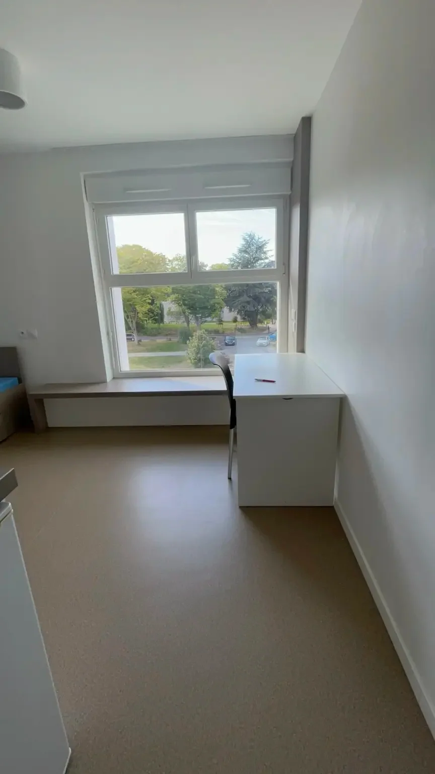 Bureau et chaise placés près de la grande fenêtre du studio