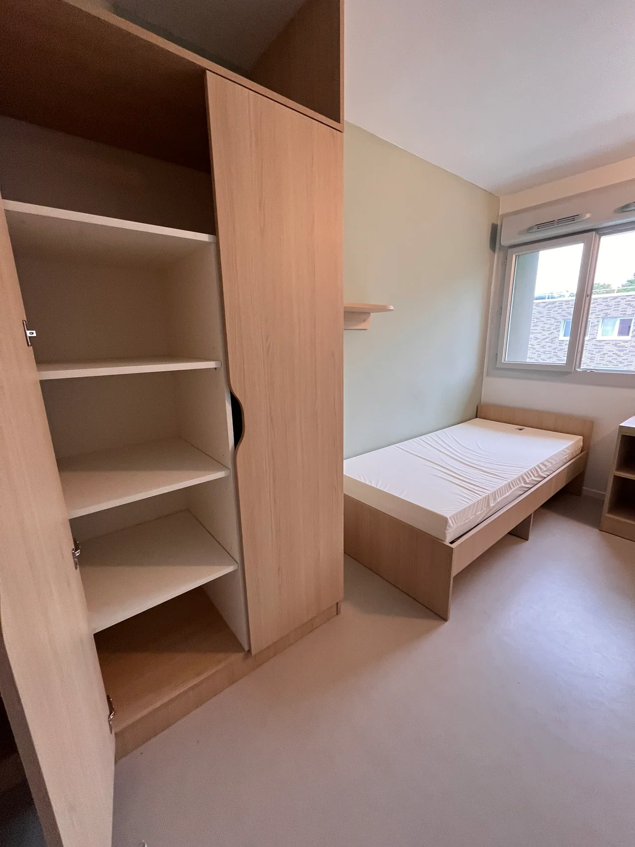 Armoire ouverte à côté du lit dans une studette du bâtiment J de la résidence Hélène-Boucher